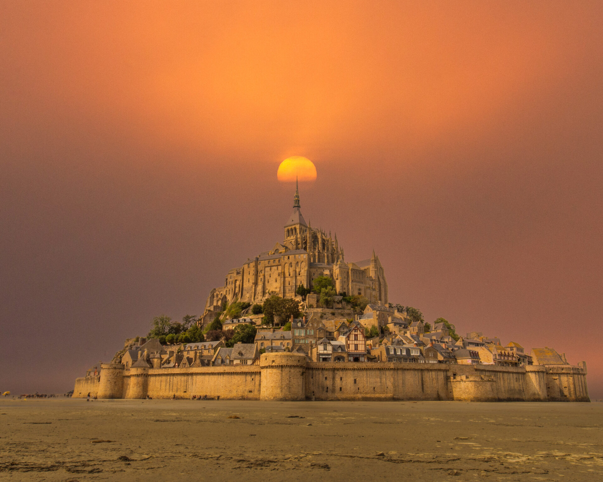 A breathtaking view of Mont Saint-Michel, a historic island commune in Normandy, France. The medieval abbey towers above the surrounding tidal waters, with cobblestone streets and charming buildings nestled along the steep hill. The scene is set against a dramatic sky, capturing the timeless beauty and mystique of this iconic landmark.