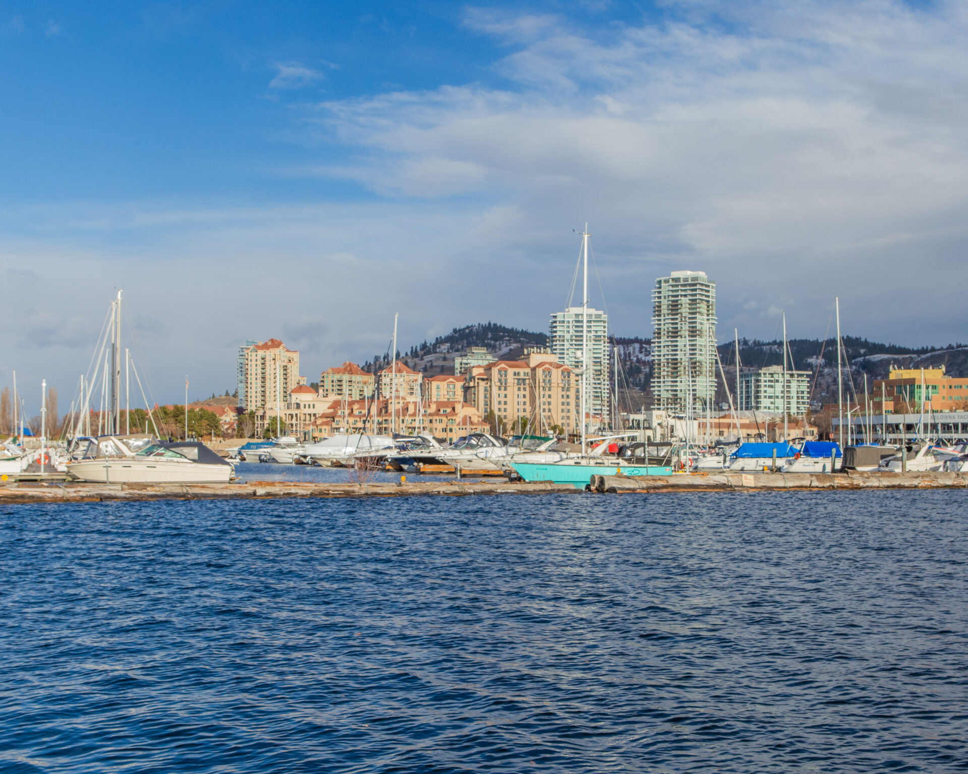 Panoramic view featuring the cityscape, mountains in the background, and boats docked at the marina.