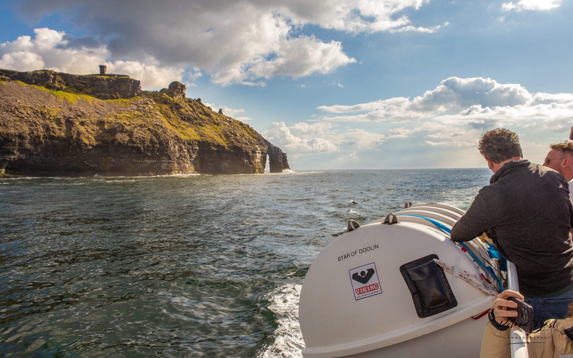 Breathtaking view of the Cliffs of Moher, with rugged cliffs towering over the Atlantic Ocean under a cloudy sky.