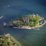 A picturesque view of Boldt Castle, an impressive historic mansion on Heart Island in the Thousand Islands region. The castle features elegant stone architecture, multiple turrets, and lush gardens surrounded by the sparkling waters of the St. Lawrence River. Gananoque, 1000 islands