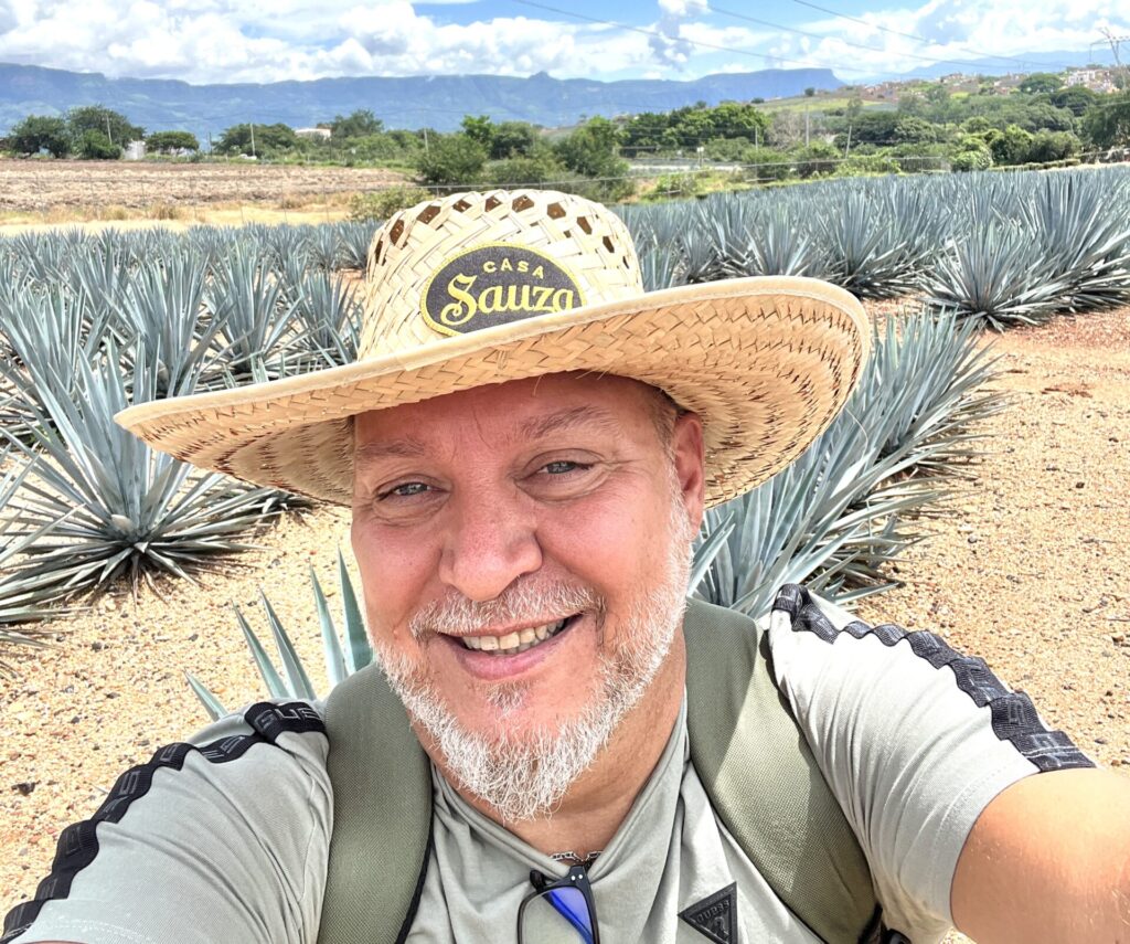 Person wearing a Suaza hat standing in a field of agave plants during a Sauza Tequila tour as I'm Exploring Tequila, Mexico